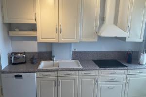 a kitchen with white cabinets and a sink at top floor apartment with private park in Montpellier