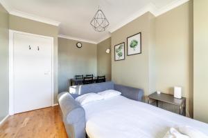 a bedroom with a large white bed and a chair at Bright and Cosy Apartment in South London in London