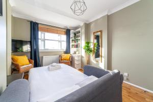 a living room with a bed and a couch at Bright and Cosy Apartment in South London in London