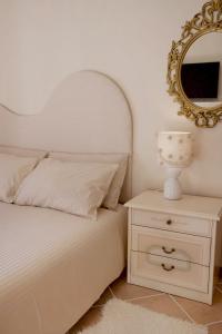 a bedroom with a bed with a mirror and a nightstand at Il Giardino di Cristina in Vagliagli