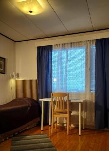 a bedroom with a table and a chair and a window at Jeppo Guesthouses in Uusikaarlepyy