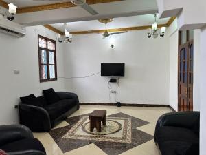 a living room with couches and a tv and a table at Pazuri apartment in Ngambo