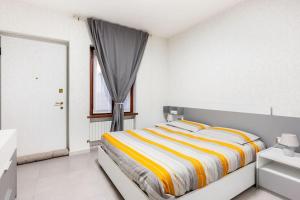 ピアチェンツァにあるCasa Maddalenaの白いベッドルーム(黄色と白のストライプのベッド付)