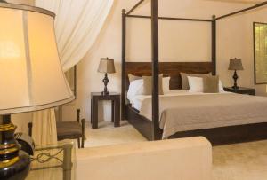 a bedroom with a canopy bed and a lamp at Hotel Hacienda Ticum in Ekmul