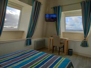 a bedroom with a bed and a desk and two windows at Hôtel le Littoral in Lézardrieux +28 photos