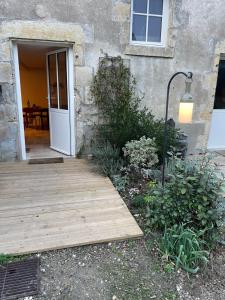 einen Holzsteg, der zu einem Haus mit einer Tür führt in der Unterkunft La cour fleurie in Neuville-aux-Bois