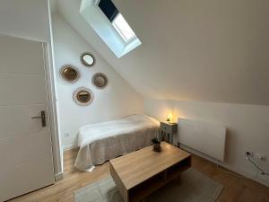 Schlafzimmer mit einem Bett, einem Tisch und einem Dachfenster in der Unterkunft La cour fleurie in Neuville-aux-Bois