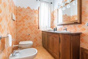 een badkamer met een toilet, een wastafel en een spiegel bij Villa Rosa in Cannigione