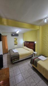 a hotel room with two beds and a television at Hosteria Amparo in Neuquén