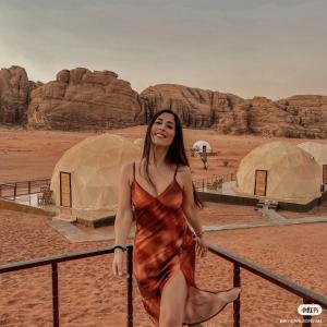 Una mujer con un vestido parada en el desierto en Bubble RumCamp en Wadi Rum