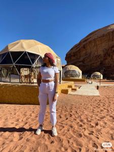 Una donna in piedi nella sabbia nel deserto di Bubble RumCamp a Wadi Rum