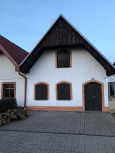 ein weißes Haus mit schwarzen Türen und einer steinernen Einfahrt in der Unterkunft Vinný sklep v Zarazicích in Veselí nad Moravou