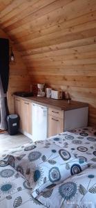 L'ERABLE - CABANE INSOLITE et COCOONING 2 personnes - CAMPING LE BEL AIR في Limogne-en-Quercy: غرفة نوم مع سرير في كابينة خشبية