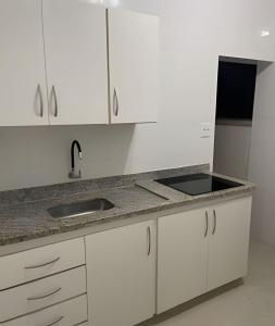 a kitchen with white cabinets and a sink at Apartamento no Centro! in Franca