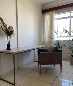 a living room with a table and a chair at Apartamento no Centro! in Franca