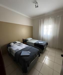 a hotel room with two beds and a window at Apartamento no Centro! in Franca