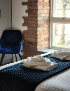 łóżko z 2 białymi ręcznikami i niebieskim krzesłem w obiekcie Maynooth Serviced Studios w mieście Maynooth