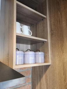 a cupboard with four white mugs in it at Maynooth Serviced Studios in Maynooth