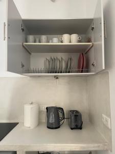 a kitchen counter with a tea kettle and dishes on shelves at Nektarios apartment in Mikri Vigla