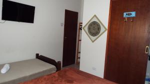a room with a bed and a door with a television at Pousada Quintal do Mar in Ubatuba