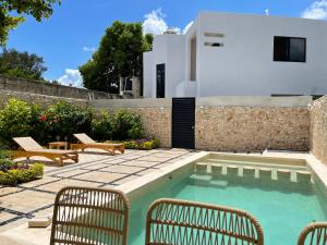 een achtertuin met een zwembad en stoelen en een huis bij LELÁA A NAJ in Mérida