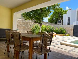 un patio con mesa de madera y sillas en LELÁA A NAJ en Mérida