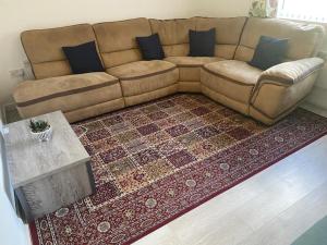 a brown couch in a living room with a rug at Cozy flat in Birmingham with Parking in Birmingham