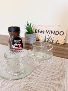uma mesa com duas chávenas de vidro e uma garrafa de bevan windo em Studio25_Apto região central Foz em Foz do Iguaçu