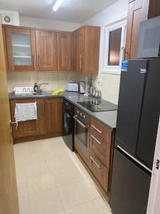 eine Küche mit Holzschränken und einem schwarzen Kühlschrank in der Unterkunft Cozy flat in Birmingham with Parking in Birmingham