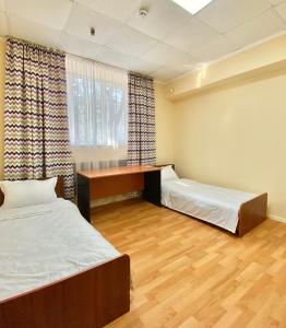 um quarto com duas camas e uma secretária em Alma-Ata Hostel em Almaty