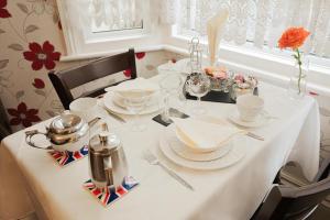 ドーバーにあるMaison Dieu Guest Houseの白いテーブルクロスと皿が置かれたテーブル