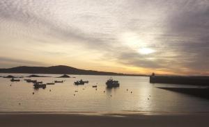 um grupo de barcos sentados na água ao pôr do sol em Céntrico apartamento en Corrubedo em Corrubedo