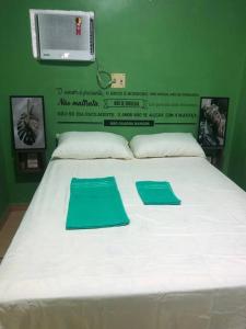 uma grande cama branca com dois tapetes verdes em Apartamento Natureza Verde Manauara em Manaus