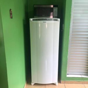 Cette chambre verte comprend un réfrigérateur blanc et un four micro-ondes. dans l'établissement Apartamento Natureza Verde Manauara, à Manaus