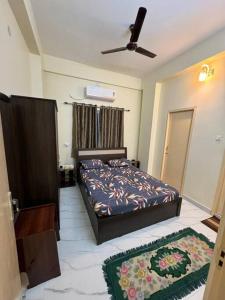 - une chambre avec un lit et un ventilateur de plafond dans l'établissement Chawali Family Home, à kolkata