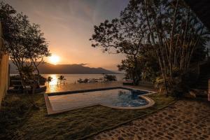 una piscina con puesta de sol en el fondo en suites vista pro mar ilhabela en Ilhabela