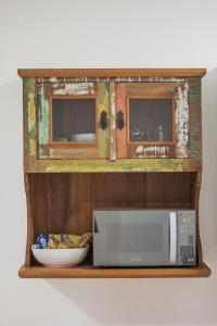 a shelf with a microwave and a bowl on it at suites vista pro mar ilhabela in Ilhabela