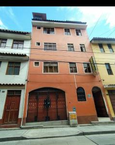 an orange building with two doors and a garage at HOSPEDAJE EL ARCO in Ayacucho