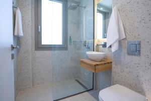 a bathroom with a glass shower and a sink at Lirides suites in Lefkada Town