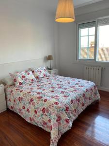 een slaapkamer met een bed met een bloemdekbed bij El Burgo in Baiona