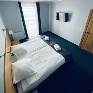 a bedroom with a bed with white sheets and a window at Hotel Galion in Gdańsk