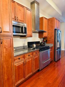 uma cozinha com armários de madeira e electrodomésticos de aço inoxidável em Entire Modern Home near Stadiums, Hospitals, and Schools em Baltimore