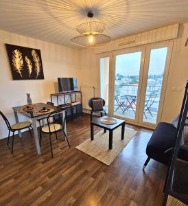 uma sala de estar com uma mesa e cadeiras e uma televisão em [Cosy] Appartement équipé avec terrasse, Wifi em Pont-de-la-Maye