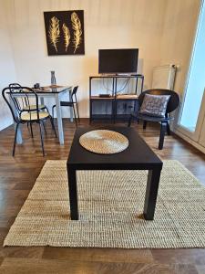 uma sala de estar com uma mesa de café preta e cadeiras em [Cosy] Appartement équipé avec terrasse, Wifi em Pont-de-la-Maye