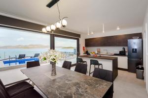 cocina y comedor con mesa y vistas al océano en Villa Nada en Drače