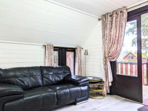 a black leather couch in a living room with a window at Danu 1A -Hot Tub-Perth-Pet Friendly-Luxury-Romantic in Perth