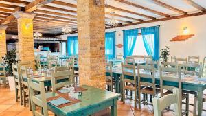un restaurant avec des tables et des chaises bleues dans une pièce dans l'établissement La Perla Hotel, à SantʼAnna Arresi