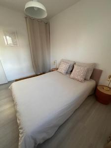 um quarto com uma grande cama branca e 2 almofadas em COSY F3 PROCHE CENTRE em Belfort