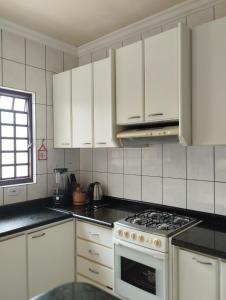 a kitchen with white cabinets and a stove top oven at Aero Hostel Londrina in Londrina
