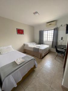 1 dormitorio con 2 camas y escritorio con silla en Pousada Flor De Brasília, en Brasilia